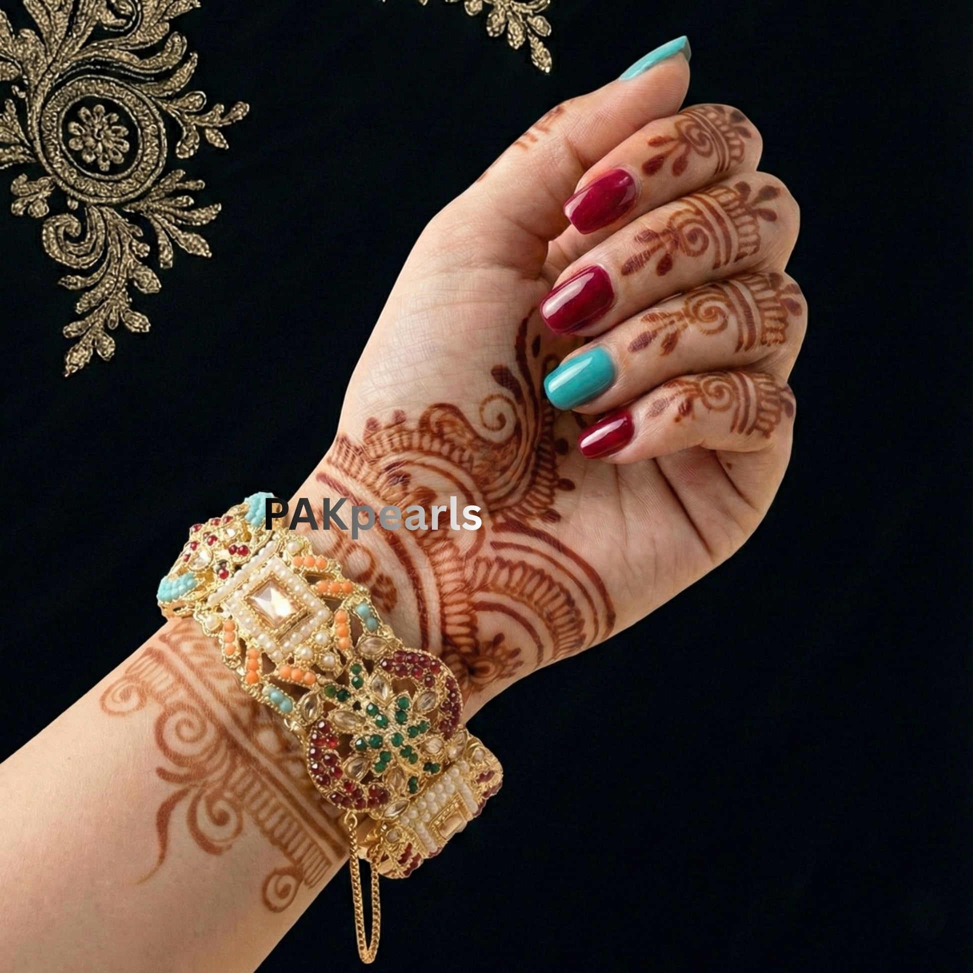 Hand wearing heavy gold Nauratan bangles from PAKpearls, showcasing the detailed craftsmanship and vibrant stone setting.